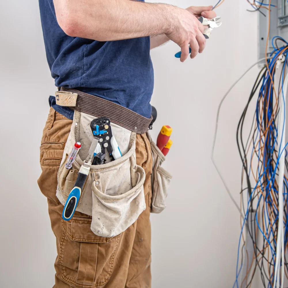 electrician-builder-work-examines-cable-connection-electrical-line-fuselage-industrial-switchboard-professional-overalls-with-electrician-s-tool